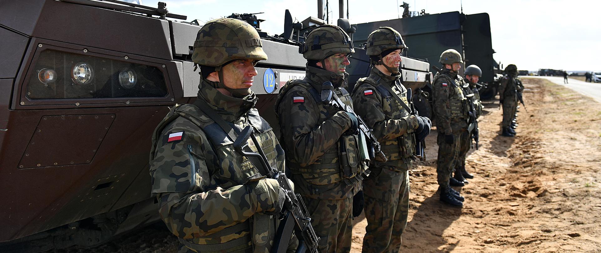 Żołnierze Wojska Polskiego w umundurowaniu polowym z bronią etatową, w tle KTO Rosomak.