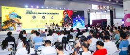 书展主舞台正在举行一场关于赛博朋克主题和波兰科幻大师拉法乌·科西克的活动。舞台上举行了作家和出版商参加的讨论会，他们身后的大屏幕上显示着与赛博朋克世界相关的海报。舞台前聚集了许多观众。