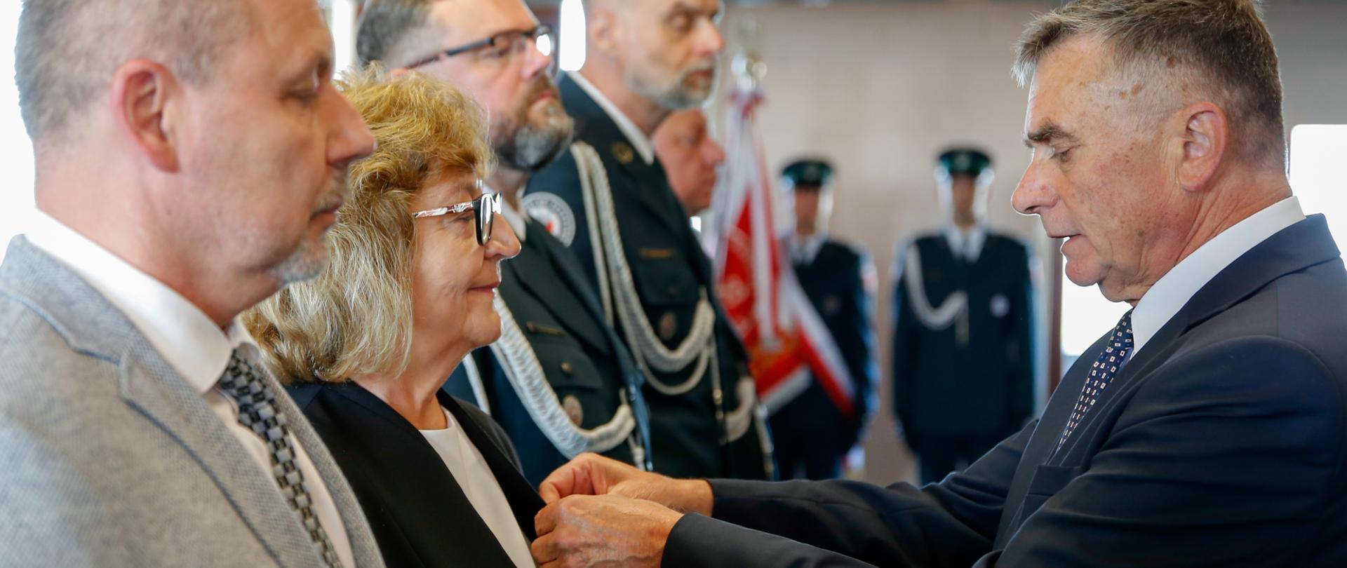 Wojewoda lubelski przypina kobiecie medal do marynarki.