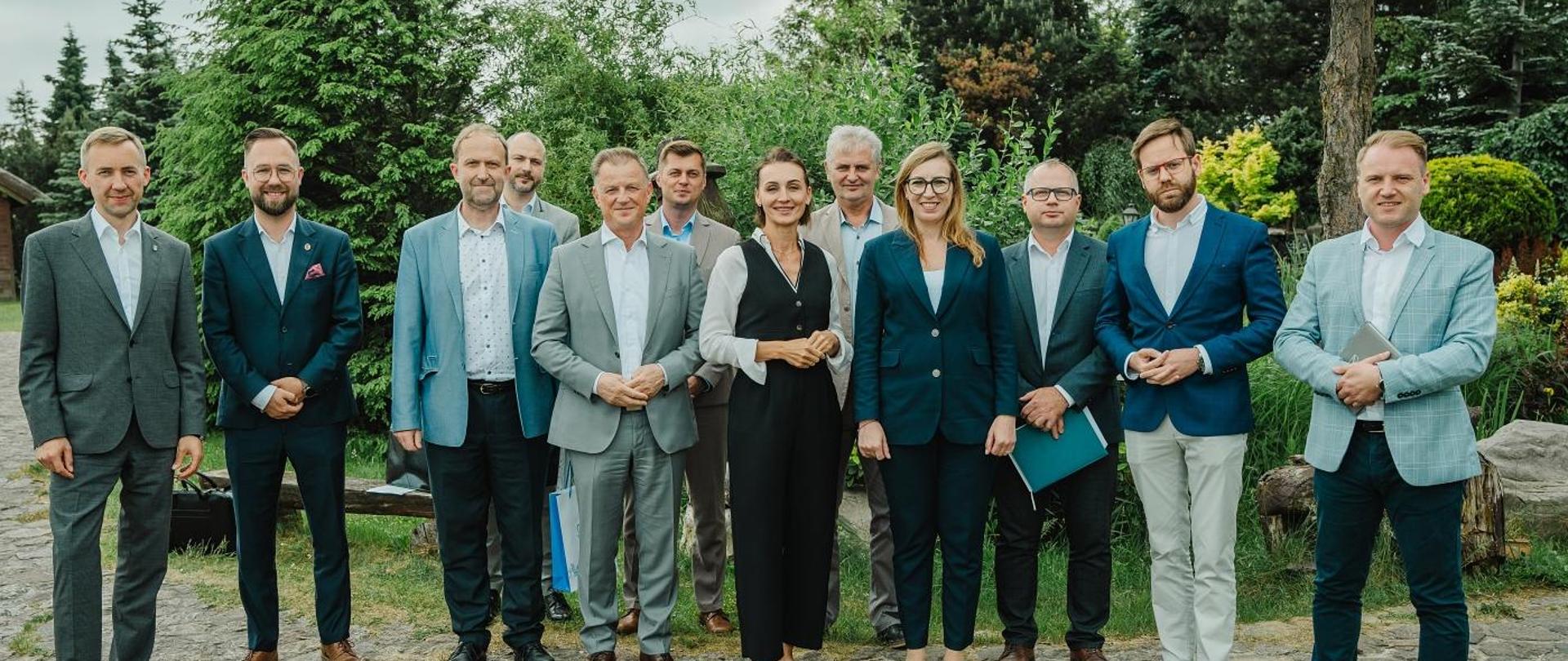 Grupa osób stoi w parku i pozuje do zdjęcia