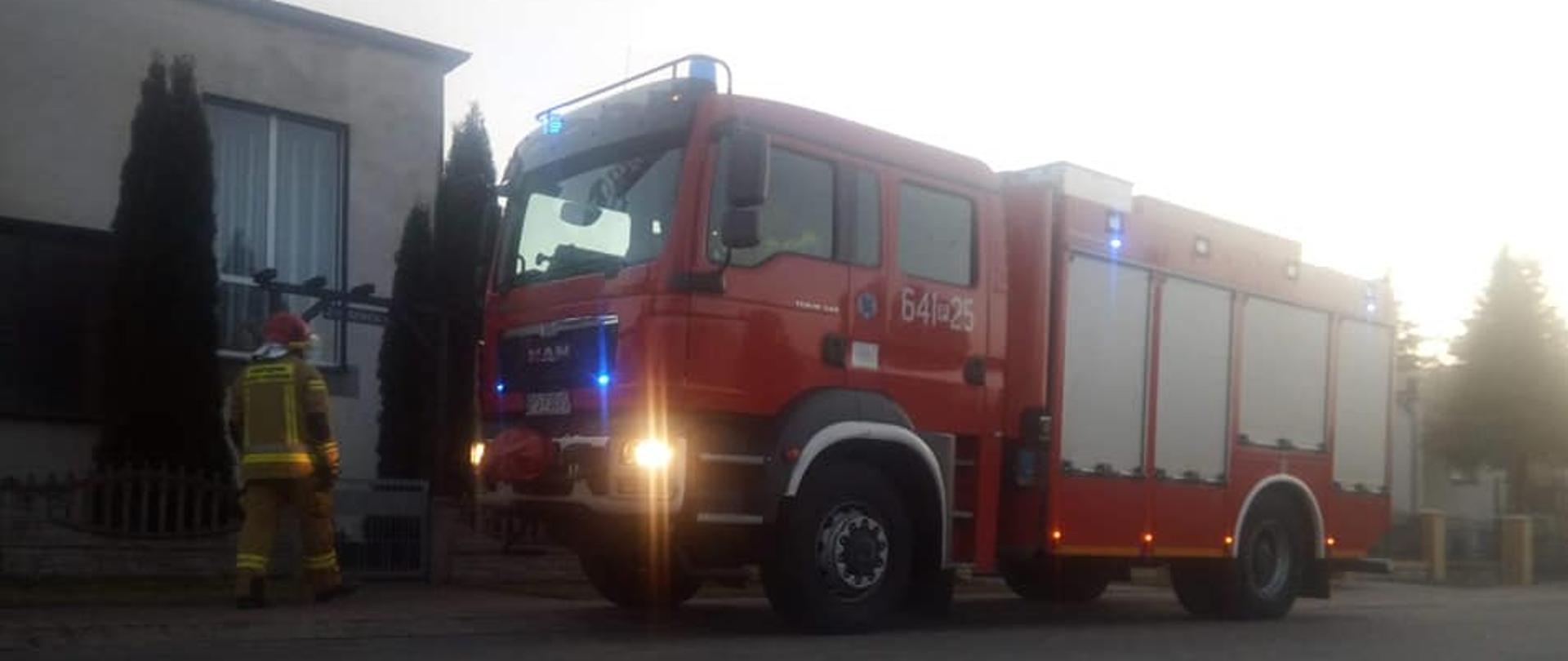 Wóz strażacki, obok strażak.