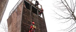 Troje ratowników wysokościowych zjeżdża na linach po ściance konstrukcji treningowej