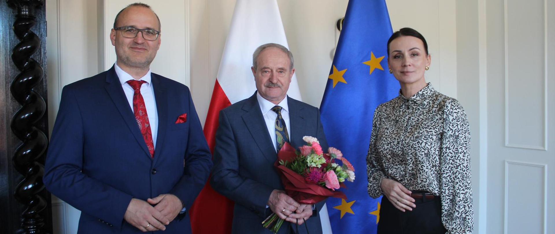 trzy osoby pozują do zdjęcia na tle polskich i unijnych flag, PUW Gdańsk, 23.04.2026 r