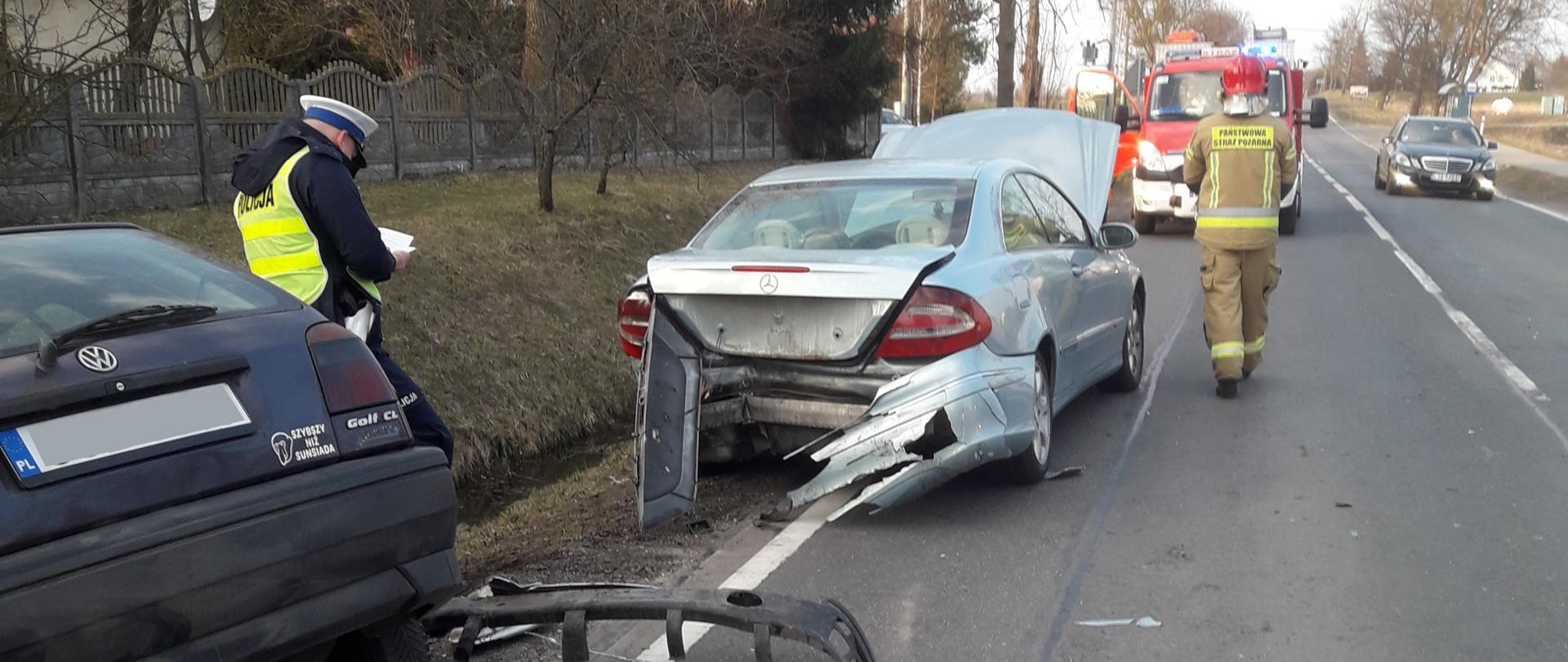 Uszkodzone pojazdy stoją na jezdni, działania prowadzą strażacy i policjanci