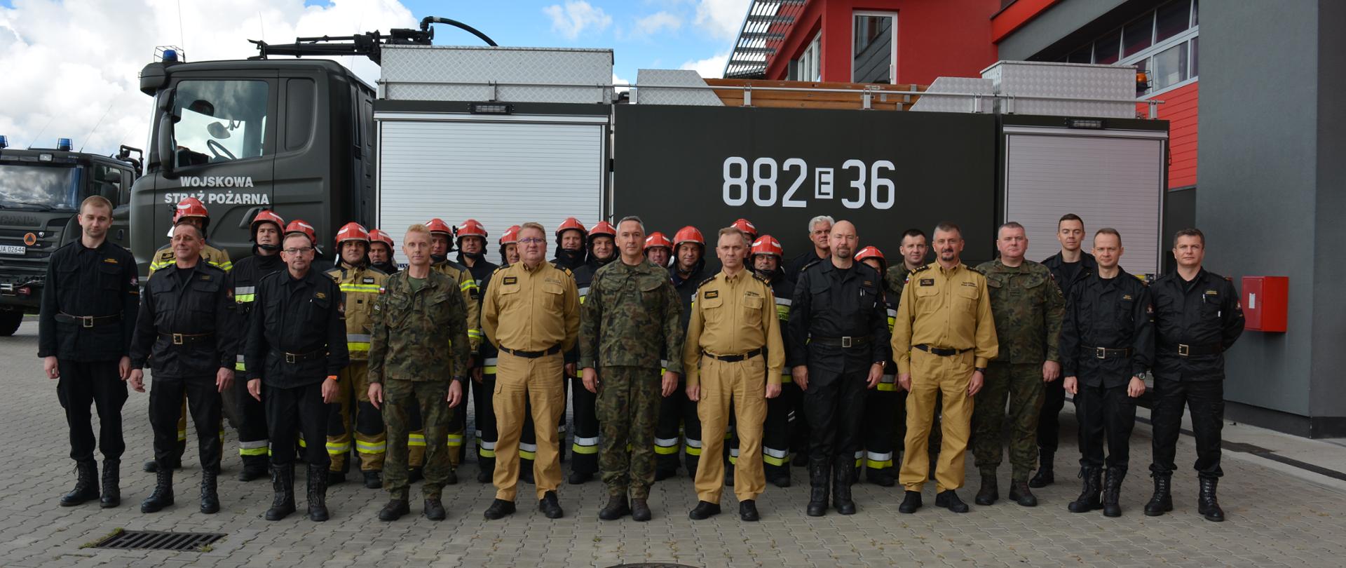 Zdjęcie przedstawia przedstawicieli Państwowej Straży Pożarnej, Wojskowej Straży Pożarnej oraz przedstawicieli Delegatury Wojskowej Ochrony Przeciwpożarowej w Bydgoszczy na tle wojskowego samochodu ratowniczo-gaśniczego. 