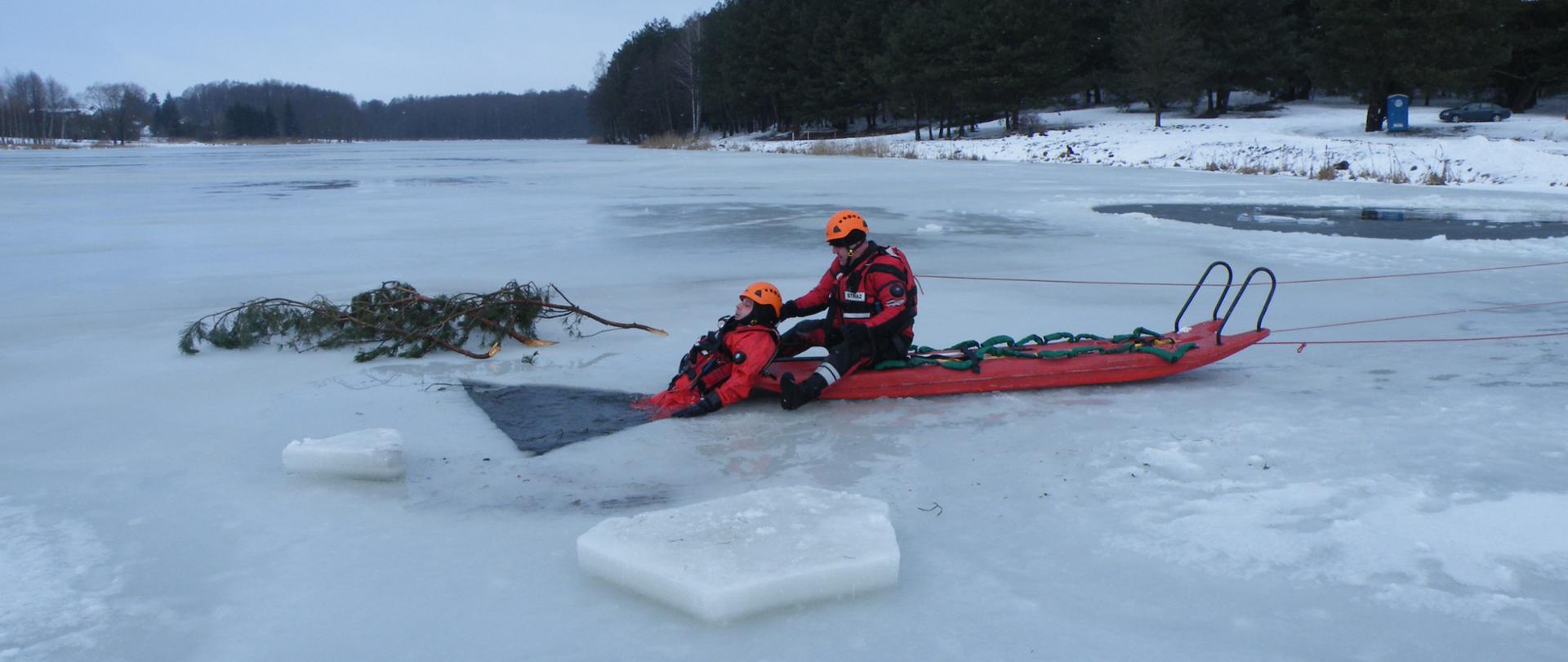 Strażak na saniach lodowych wyciąga osobę pod którą załamał się lód