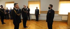 Zdjęcie przedstawia Zastępcę Podlaskiego Komendanta Wojewódzkiego Państwowej Straży Pożarnej starszego brygadiera Roberta Dzierżka podczas przyjmowania meldunku od zdającego obowiązki Komendanta Powiatowego Państwowej Straży Pożarnej w Zambrowie brygadiera Macieja Krajewskiego oraz nowo powołanego Komendanta Powiatowego Państwowej Straży Pożarnej w Zambrowie starszego brygadiera Krzysztofa Konickiego. Komendanci ubrani w mundury wyjściowe ze sznurem galowym. Uroczystość odbywała się w jednym z pomieszczeń Komendy Powiatowej Państwowej Straży Pożarnej w Zambrowie.