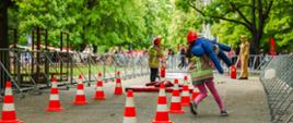 Stanowisko z torem przeszkód na którym zadania wykonują dzieci ubrane w specjalne mundury imitujące strażackie.