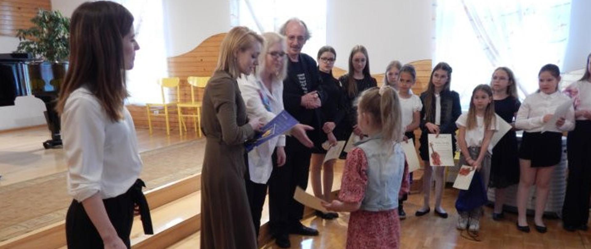 nauczyciele wręczający dyplomy uczniom