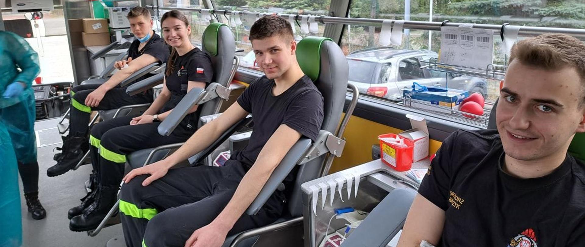 W specjalnym autobusie-ambulansie do pobierania krwi siedzi na fotelach czworo dawców-kadetów Centralnej Szkoły PSP (kobieta oraz trzech mężczyzn)