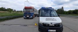 Na pierwszym planie: przód oznakowanego furgonu mazowieckiej Inspekcji Transportu Drogowego. W tle: za radiowozem ITD stoi nienormatywny zestaw z dwoma kontenerami 20-stopowymi.