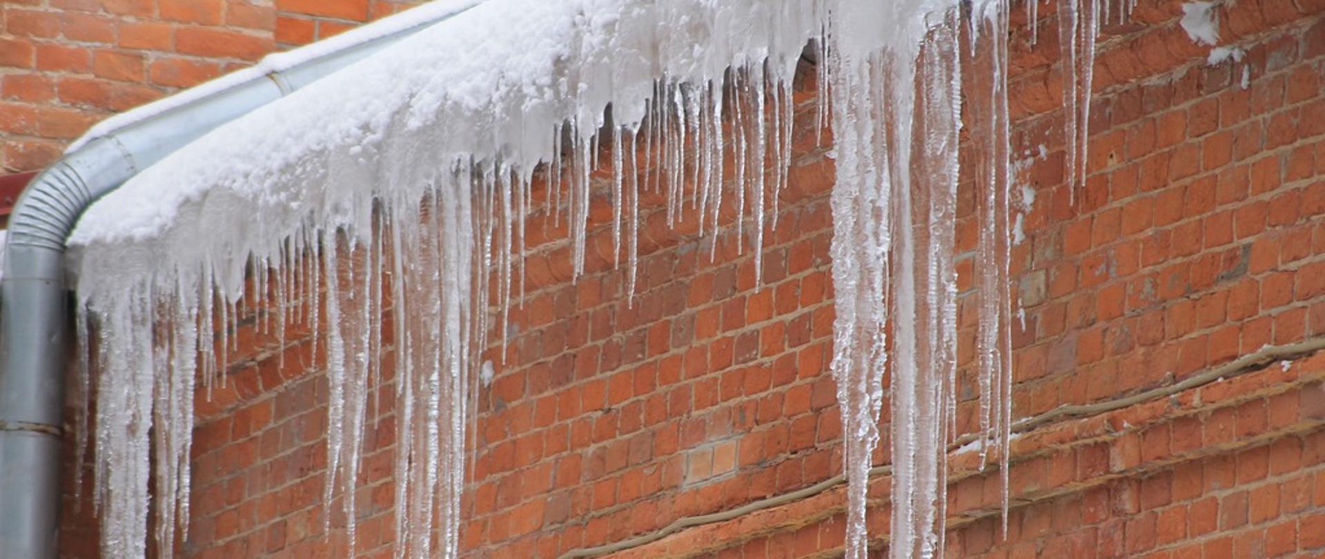 Zdjęcie przedstawia sople zwisające z okapu