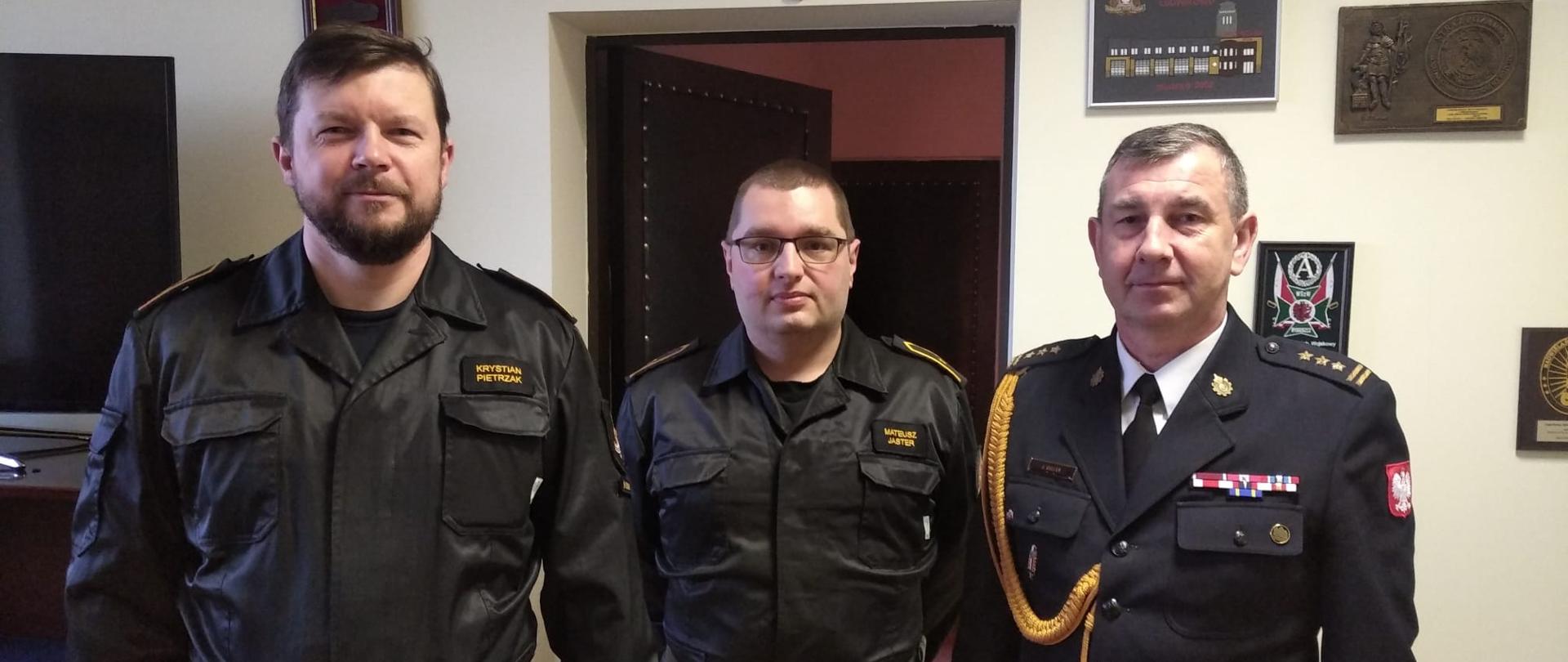 Od lewej dwaj dyżurni Stanowiska Kierowania w czarnych ubraniach sztabowych, z prawej st. bryg. Janisław Buller Komendant Miejski PSP w Bydgoszczy. 