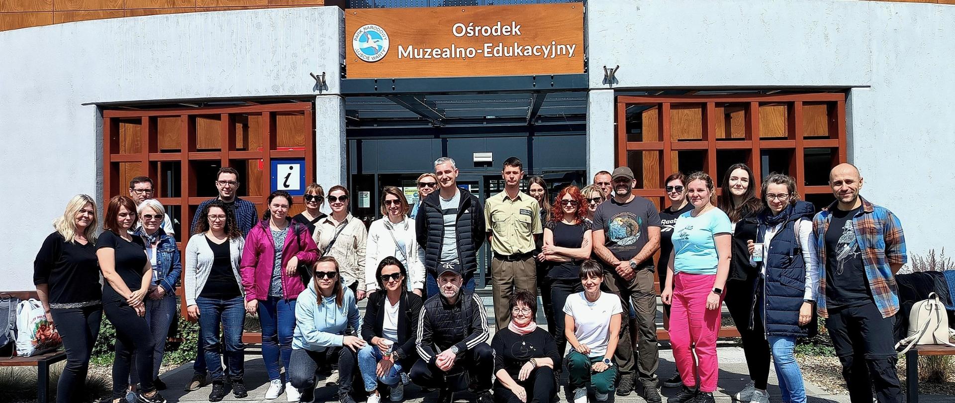 Grupa kilkudziesięciu osób pozuje do zdjęcia przed budynkiem ośrodka muzealno-edukacyjnego w Słońsku.