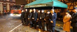 Na zdjęciu widać uroczystość przekazania nowego samochodu dla jednostki OSP Łobżenica. Jest ciemno, wieczór, delikatna mgła. 
