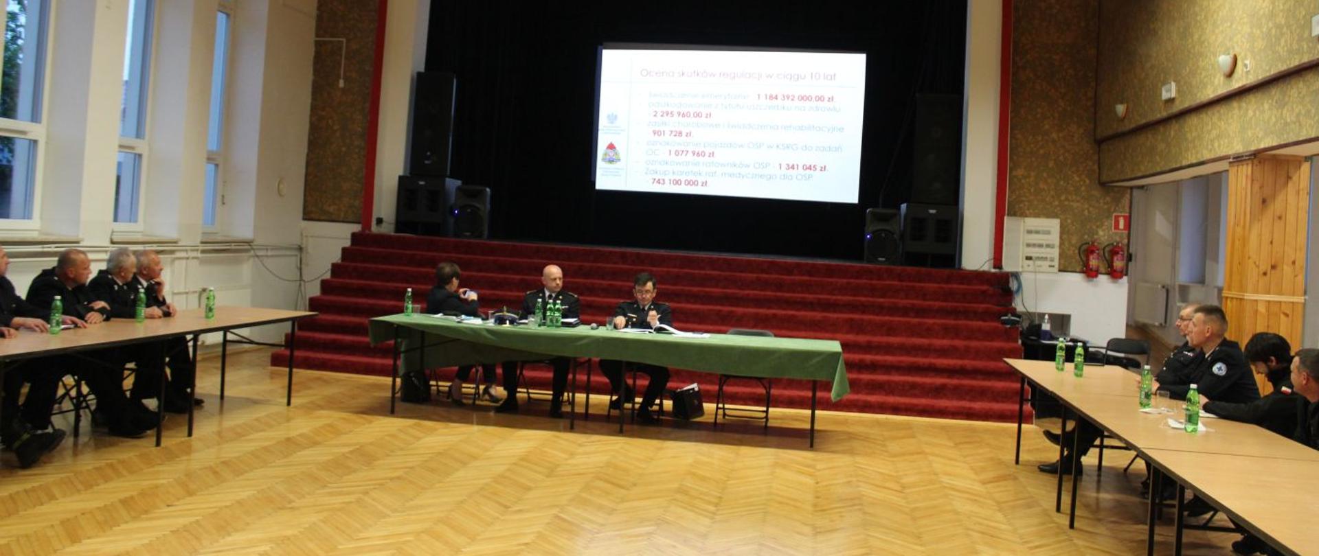 Konsultacje projektu ustawy o Ochotniczej Straży Pożarnej w powiecie dębickim , strażacy w mundurach wyjściowych siedzą przy stolikach w sali o jasnych ścianach 