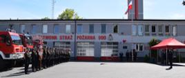Zdjęcie pokazujące całokształt uroczystości na tle budynku Komendy, z lewej strony dowódca z pododdziałem, poczty, a za nimi samochody pożarnicze; z prawej strony Dowódca uroczystości oraz Komendant Powiatowy PSP z zaproszonymi gośćmi