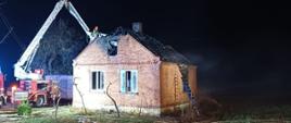 Budynek mieszkalny po pożarze. W tle samochód strażacki ze strażakami