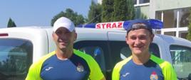 Dwaj funkcjonariusze KP PSP Środa Wielkopolska na tle pojazdu służbowego w koszulkach Państwowej Straży Pożarnej przed biegiem
