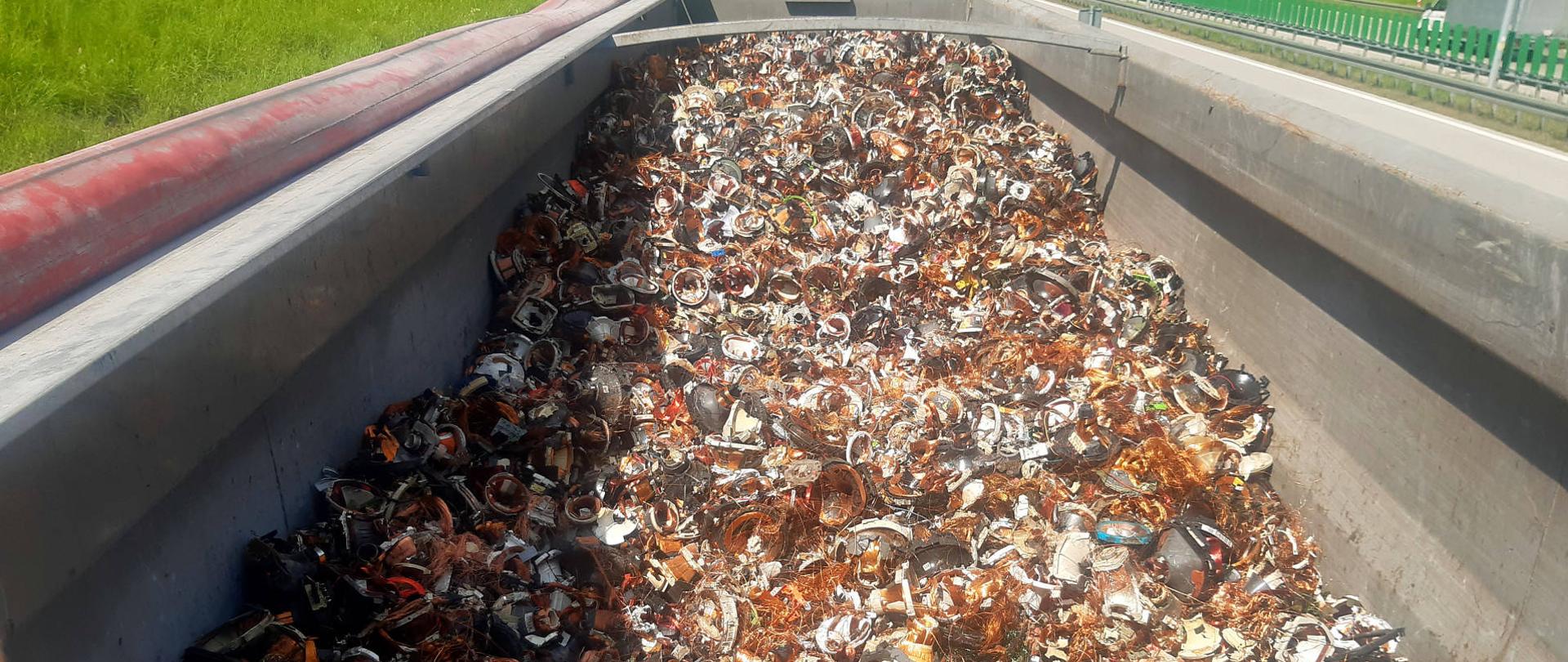 Widok z góry na wnętrze naczepy wypełnionej zużytymi cewkami elektrycznymi.