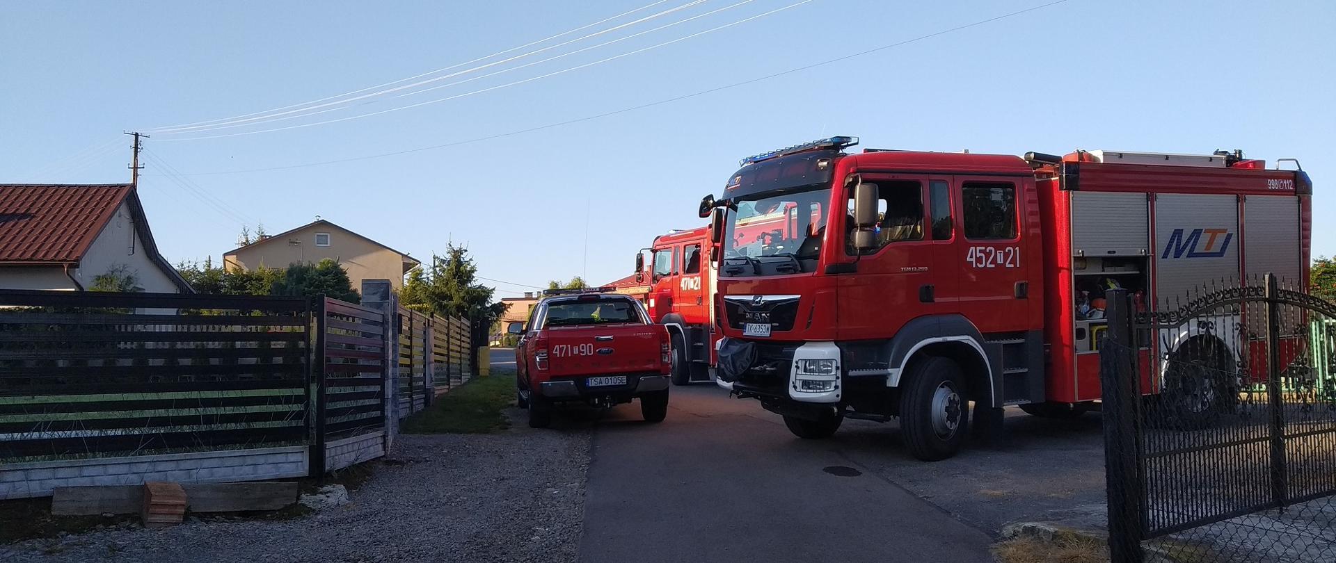 Zdjęcia zrobione w pogodny poranek. przedstawia samochody strażackie ustawione pomiędzy zabudowaniami.