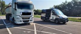 Od lewej: ciągnik siodłowy z podpiętą naczepą - wywrotką. Samochód ciężarowy stoi kołami pierwszej osi na przenośnych wagach inspekcyjnych. Obok zestawu, po jego lewej stronie, stoi oznakowany furgon mazowieckiej Inspekcji Transportu Drogowego z odsuniętymi drzwiami.