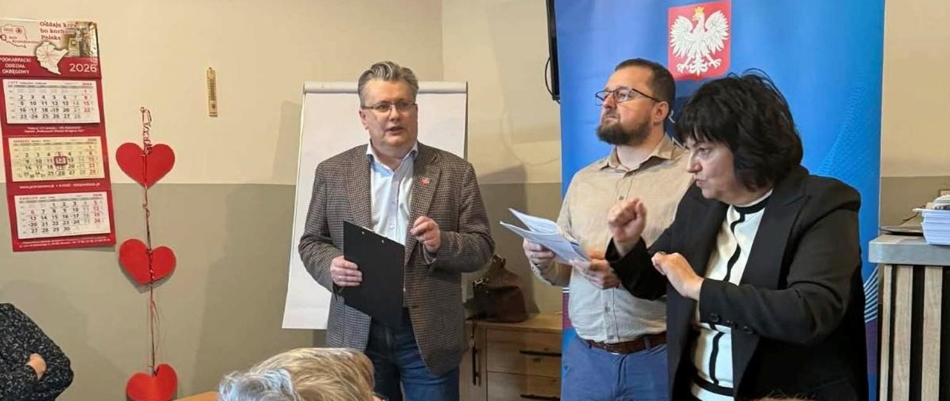 Przedstawiciele podkarpackiej KAS oraz tłumacz języka migowego stoją przed uczestnikami spotkania.
