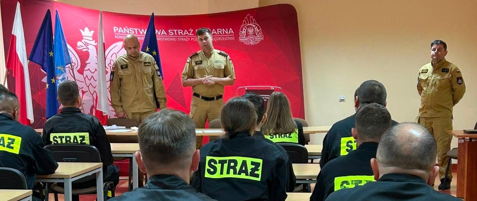 Na zdjęciu strażacy ochotniczych straży pożarnych na zakończeniu szkolenia podstawowego. Strażacy w ubraniach koszarowych znajdują się na Sali wykładowej. 