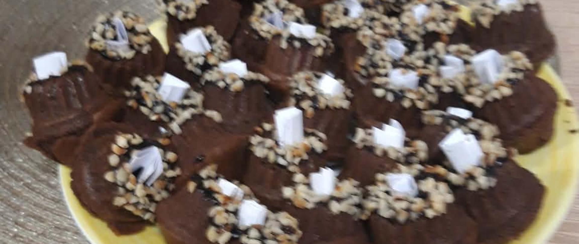 Zdjęcie talerza ze słodkimi babeczkami w środku karteczki z wróżbą