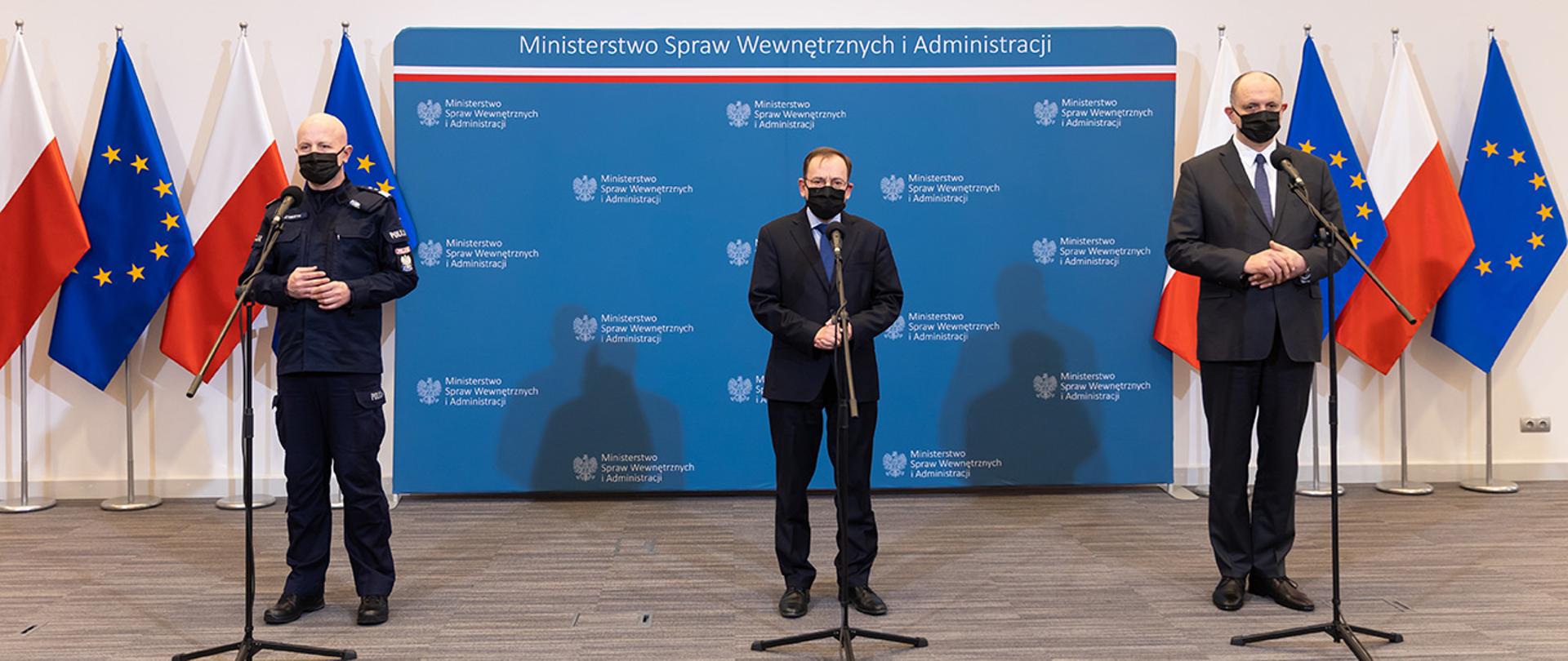 Na zdjęciu widać przemawiającego ministra Mariusza Kamińskiego. Obok stoją nadinsp. Jarosław Szymczyk komendant główny Policji i Krzysztof Saczka główny inspektor sanitarny.