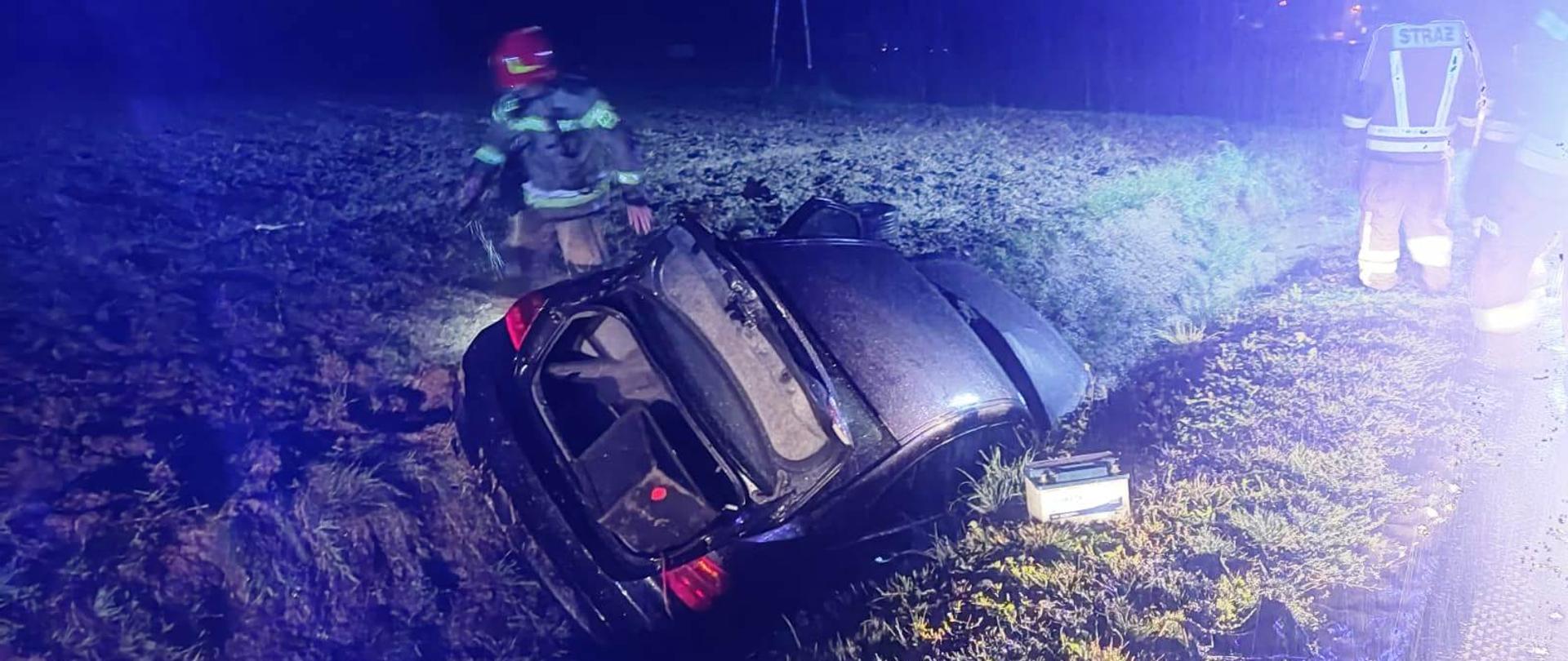 Samochód osobowy w rowie a obok strażacy