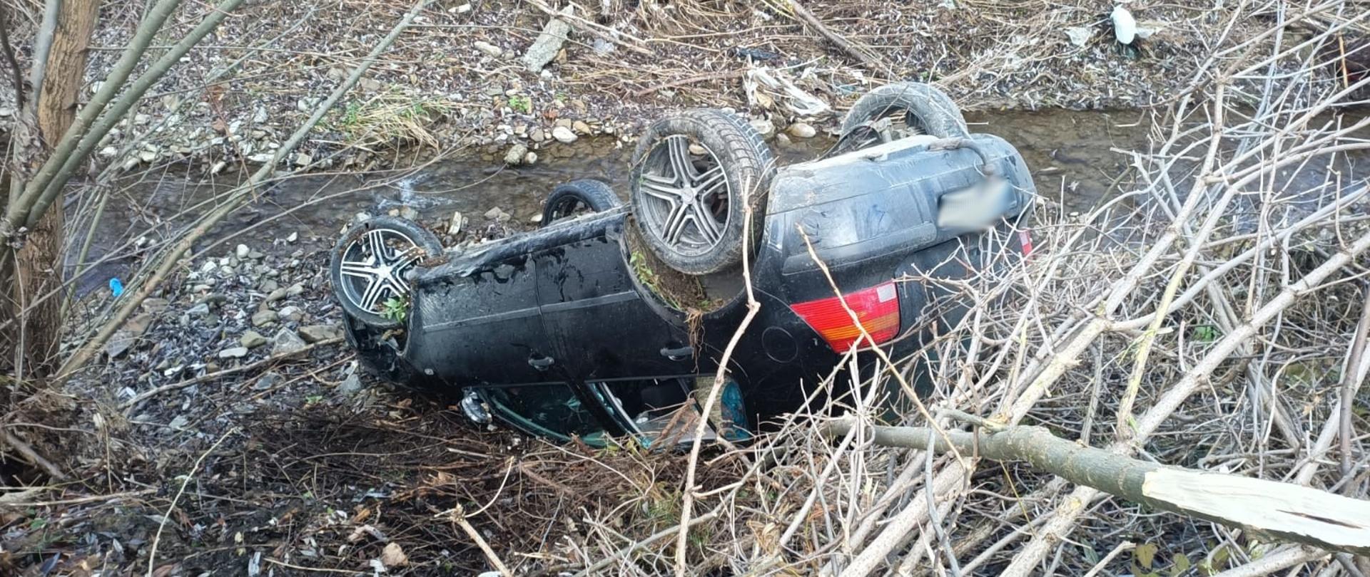 Samochód osobowy na dachu w korycie poroku.