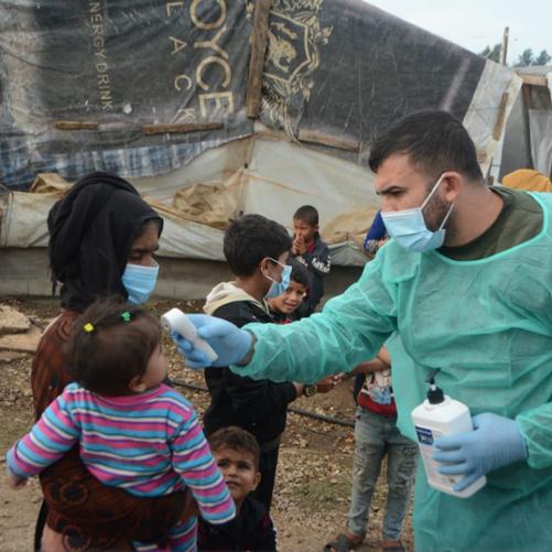 lekarz mierzy temperaturę kobiecie z dzieckiem na ręku