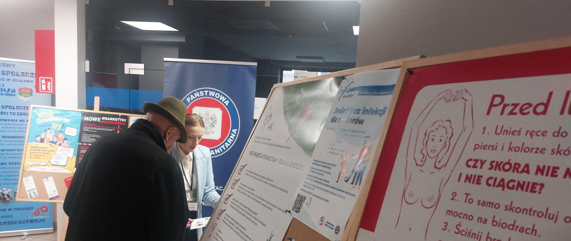 pracownik PSSE w Sosnowcu przy stoisku edukacyjnym, przekazuje materiały informacyjne