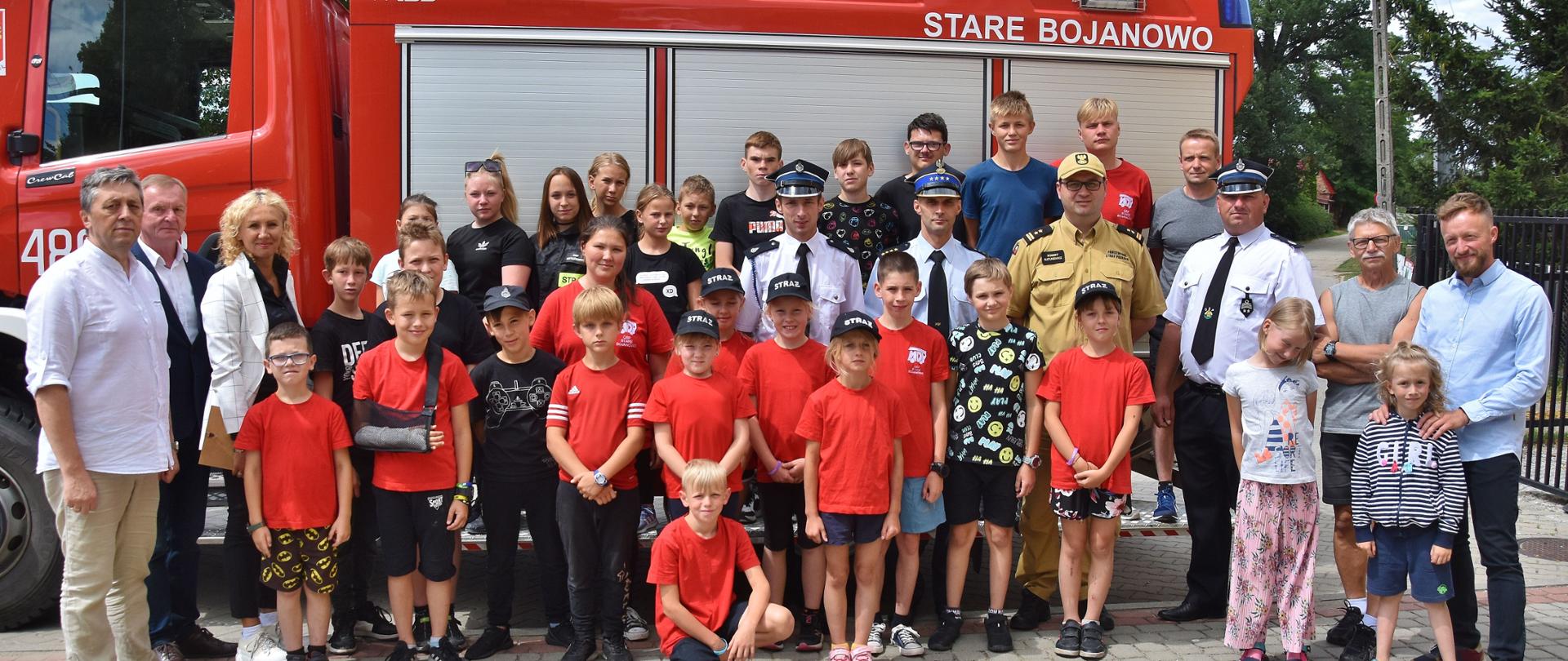 Obóz MDP Stare Bojanowo. Grupa ludzi, uczestników obozu wspólnie pozuje do pamiątkowego zdjęcia na tle samochodu pożarniczego.