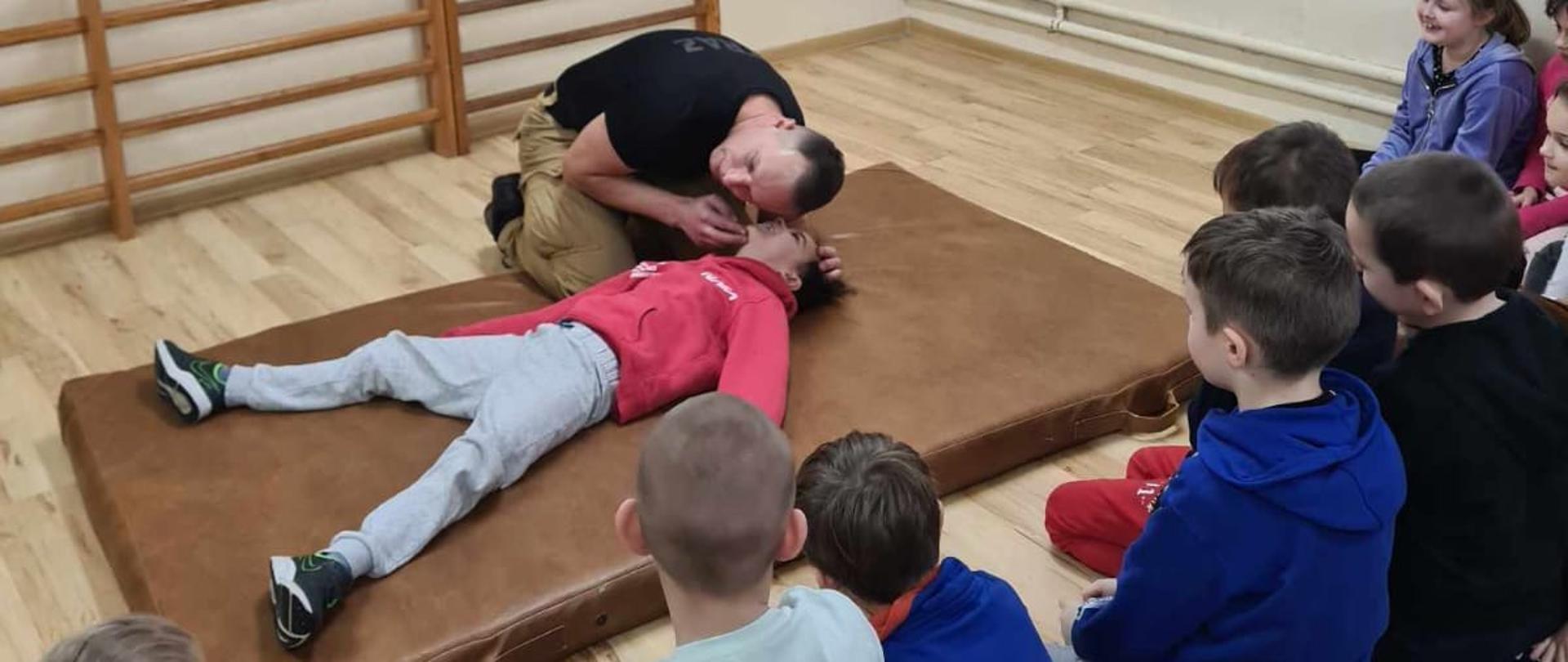 strażak udzielający instruktażu z zakresu pierwszej pomocy przedmedycznej 