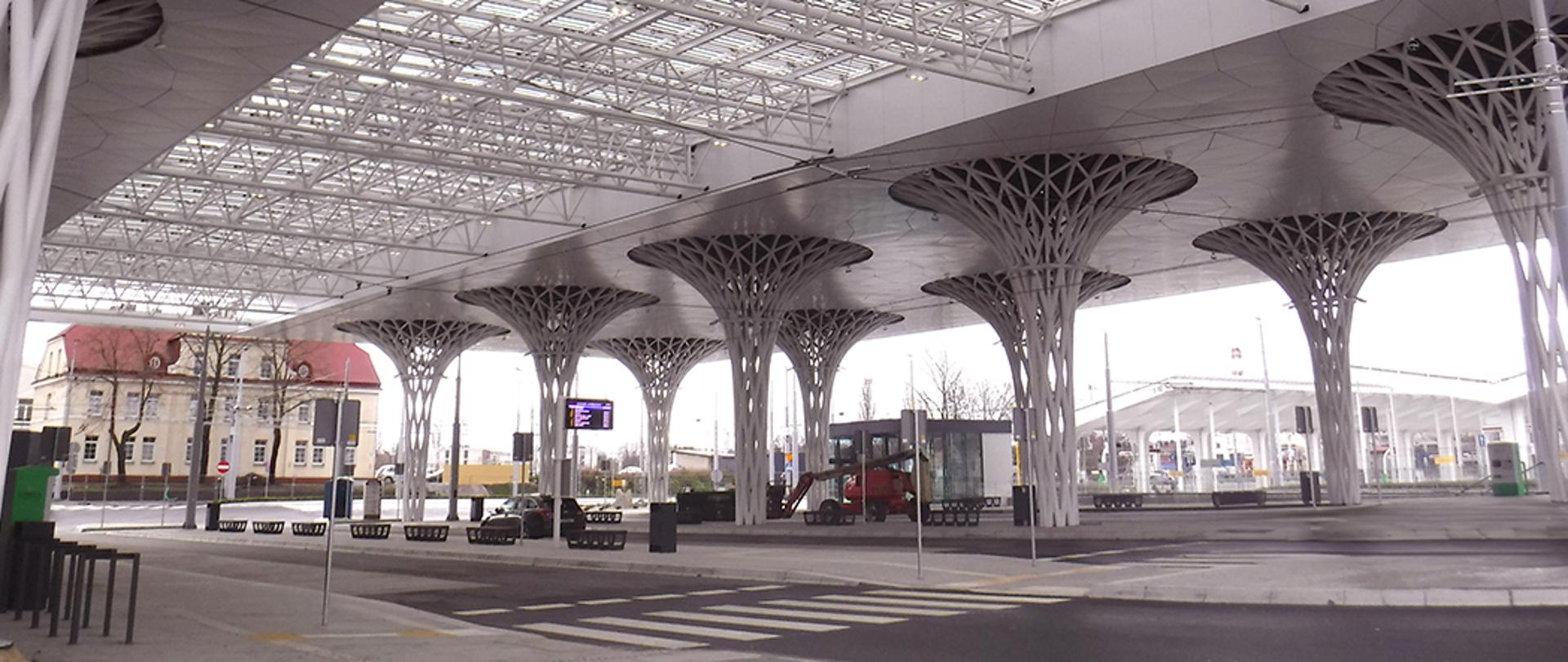 Nowoczesny, ekologiczny dworzec autobusowy w Lublinie z przeszklonym dachem i kolumnami w kształcie drzew.
