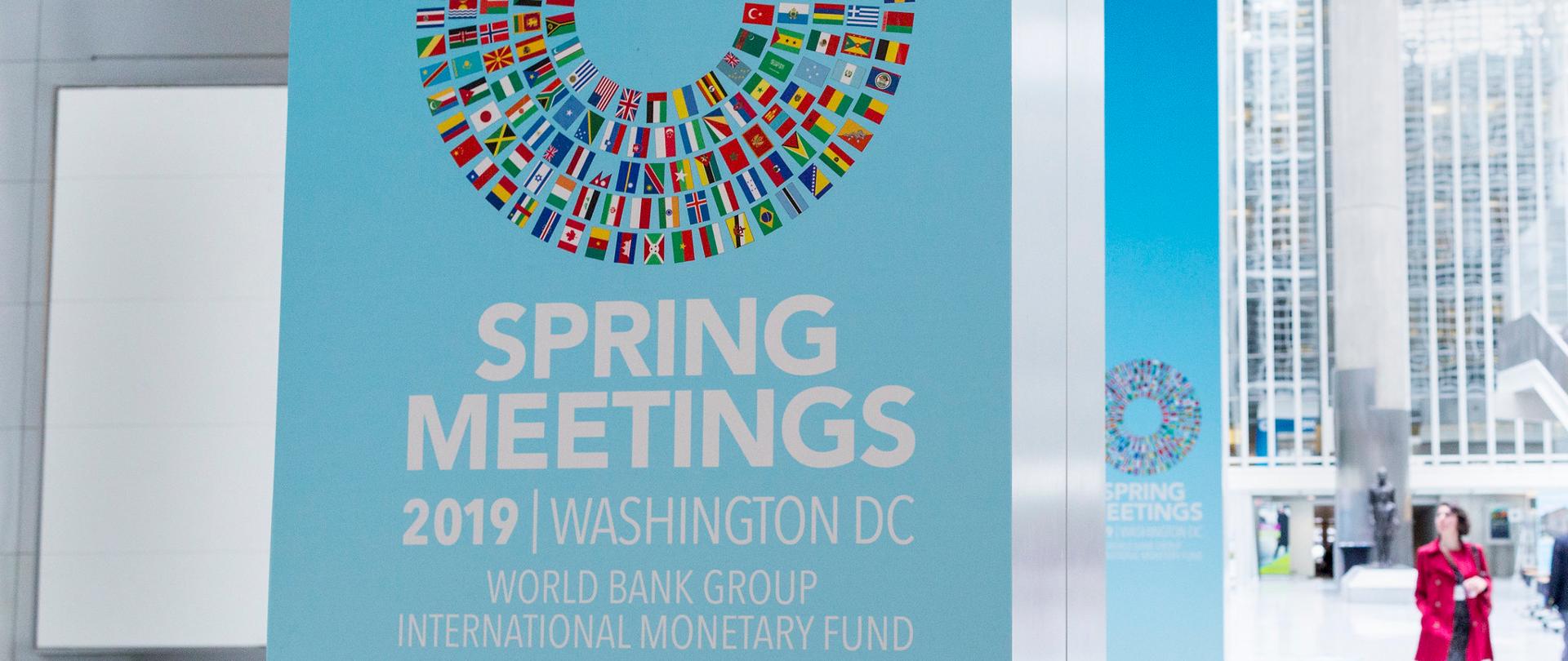 Napis na stojaku reklamowym Spring Meetings 2019 oraz flagi państw-uczestników