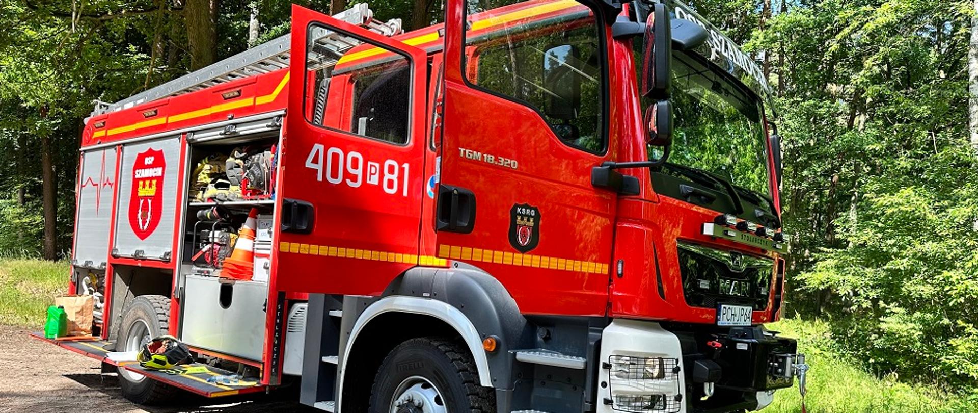 Zdjęcie przedstawia strażaków podczas szkolenia doskonalącego z obsługi pilarki.
W tle las.
