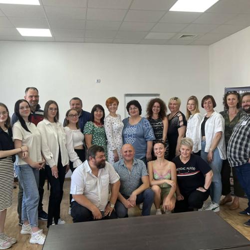 Grupa kobiet i mężczyzn w różnym wieku pozuje do zdjęcia w sali wykładowej