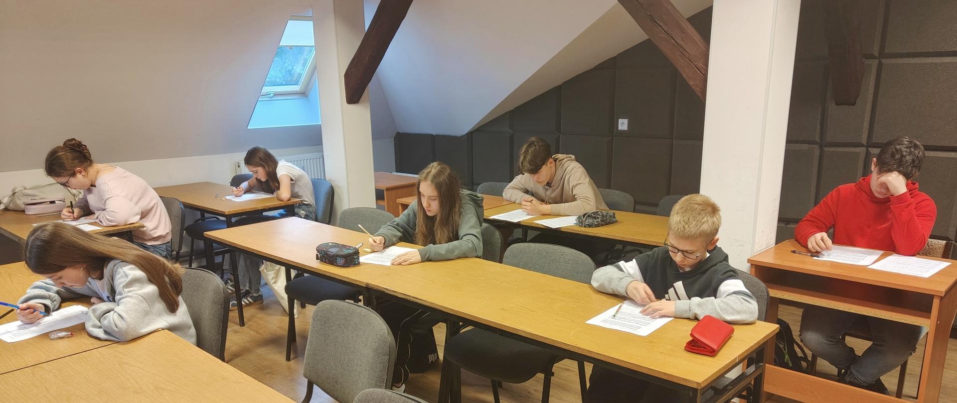 uczniowie siedzący w ławkach podczas szkolnego konkursu wiedzy teoretyczno-muzycznej