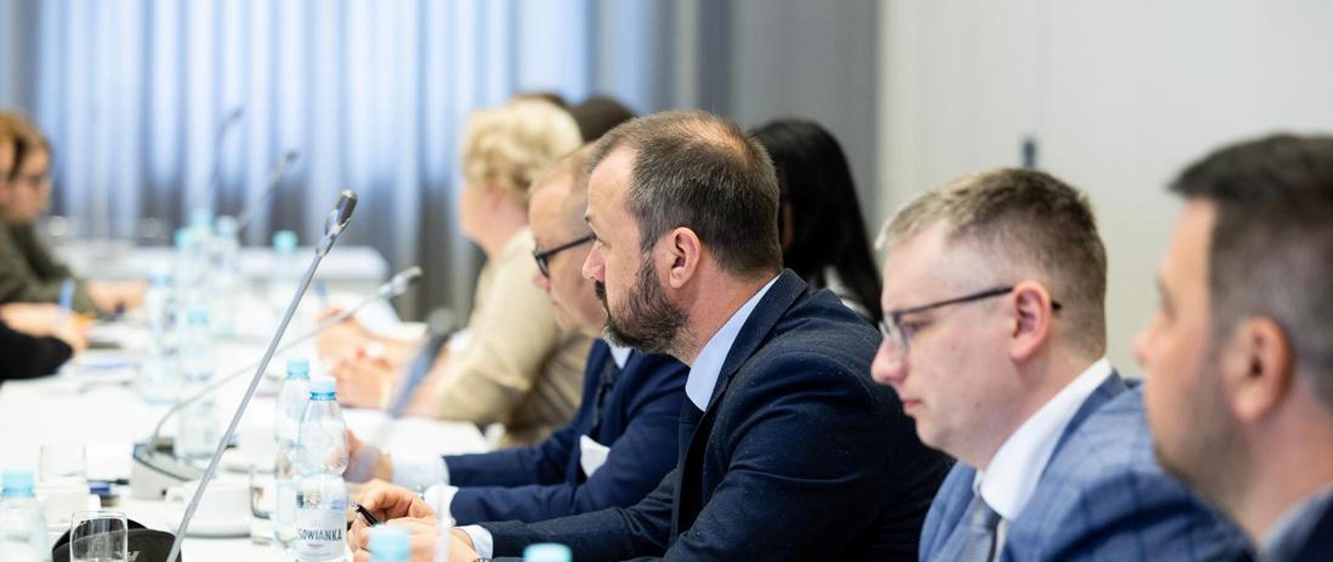 Kilka osób siedzi przy stole i rozmawia