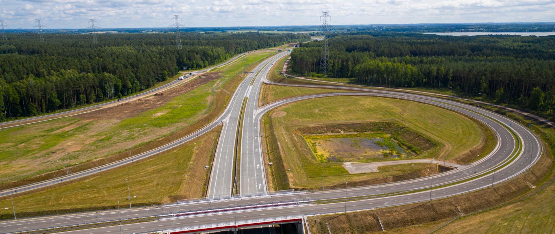 Węzeł drogowy na tle lasu. Na horyzoncie widoczne jest jezioro.
