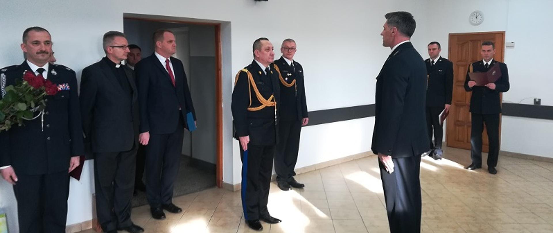 Zdjęcie przedstawia przyjęcie meldunku przez Komendanta Wojewódzkiego, strażacy ubrani są w mundury wyjściowe na zdjęciu jest również starosta powiatu olkuskiego oraz kapelan strażaków