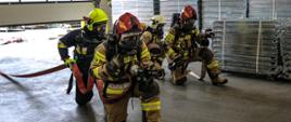 Na zdjęciu widoczni strażacy z Państwowej Straży Pożarnej i Ochotniczych Straży Pożarnych ćwiczeń taktyczno-bojowych na zakładzie TLC Ocynkownia & Packing Center w Gorlicach. Strażacy ubrani w ubrania bojowe koloru piaskowego w hełmach czerwonych i białych.