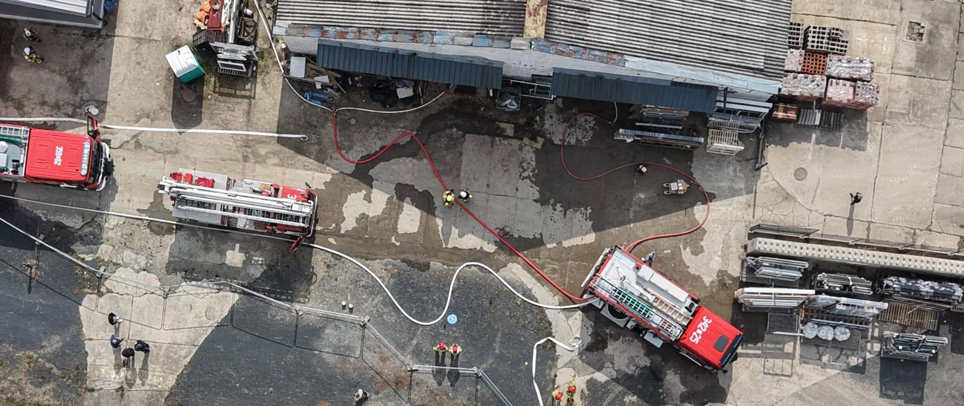 Na zdjęciu przedstawiono pojazdy strażackie i palący się budynek