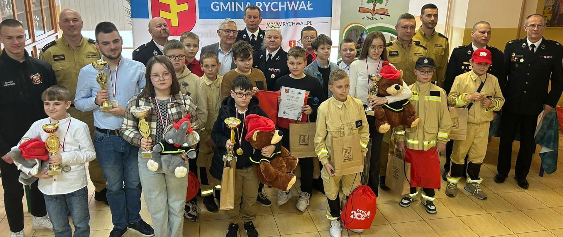 Zdjęcie przedstawia strażaków, druhów oraz uczestników turnieju wiedzy pożarniczej. 