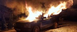 Palący się cały samochód osobowy. Płomienie wychodzą z kabiny pojazdu. 