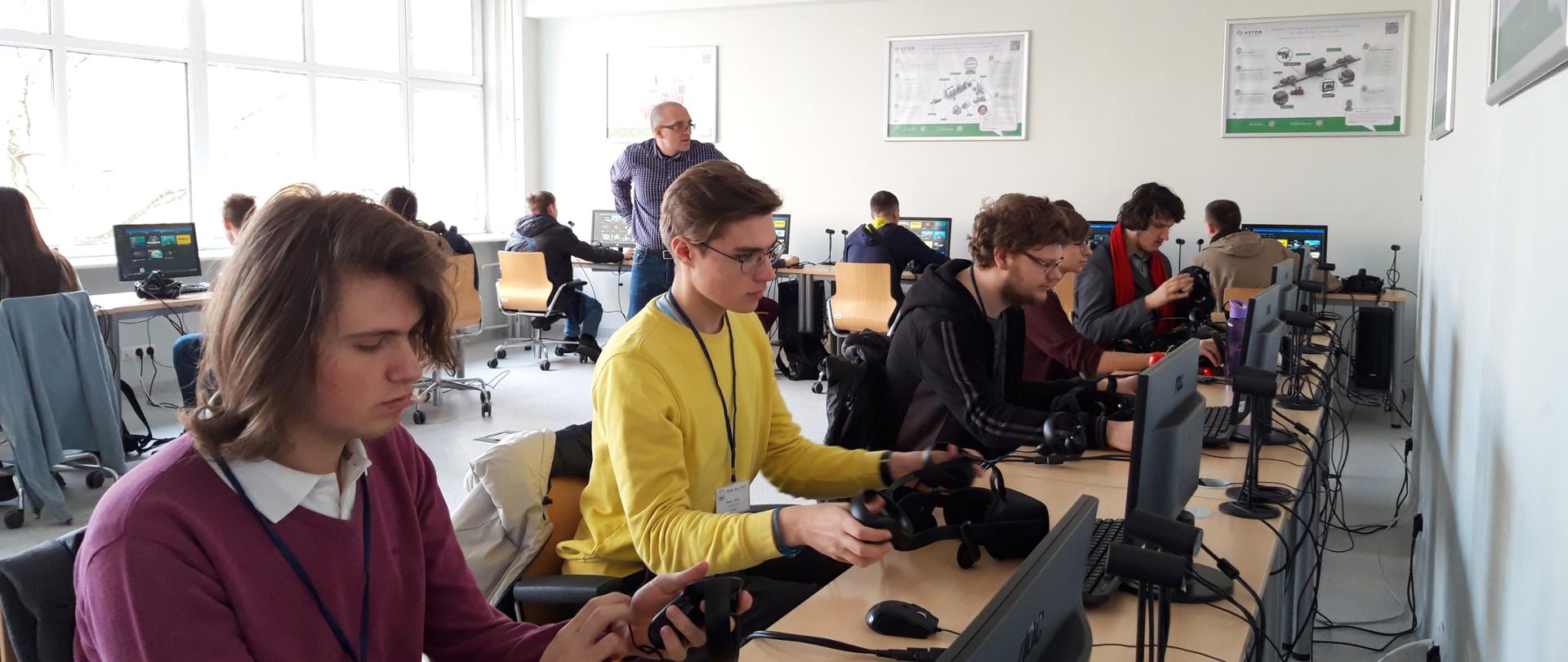 Zawodnicy siedzą przy komputerach i rozwiązują zadania matematyczne