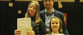 zdjęcie na sali koncertowej, z lewej uczennica Gabriela Tokarska, z prawej Hanna Przygoda za nimi nauczyciel PSM Pan Marcin Trzebiński 